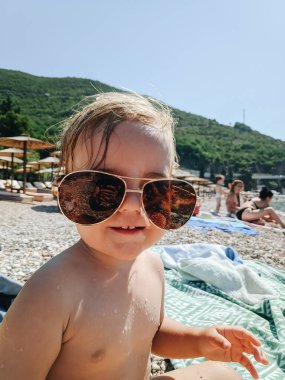 Sahilde büyük güneş gözlüğü takan bir çocuğun yakın plan portresi..