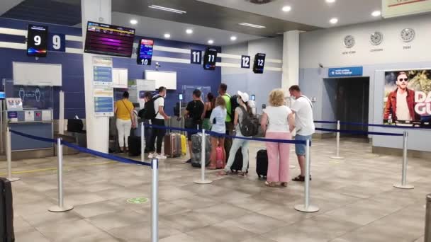 Tivat, Karadağ - 29 Temmuz 2020: Yolcular sırada bekliyor, kuralları ihlal ediyorlar, 2 metre mesafe koymuyorlar. Havaalanındaki turistler, yüzlerinde sağlık maskeleri, kontrol için bekliyorlar.. — Stok video