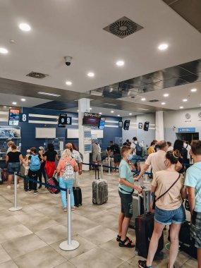 Tivat, Karadağ - 29 Temmuz 2020: Yolcular sırada bekliyor, kuralları ihlal ediyorlar, 2 metre mesafe koymuyorlar. Havaalanındaki turistler, yüzlerinde sağlık maskeleri, kontrol için bekliyorlar..