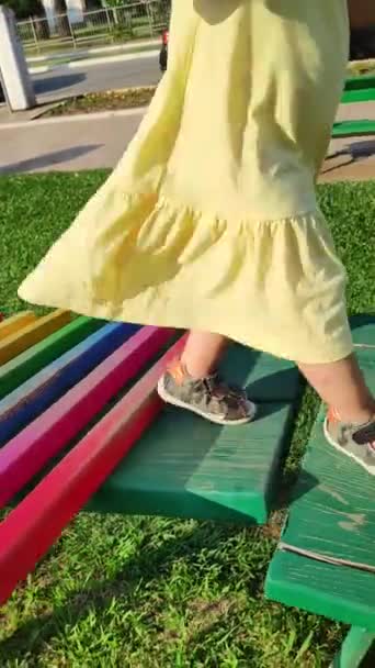 Tata trzyma córkę za rękę i pomaga jej chodzić po drewnianym zjeżdżalni dla dzieci. 1-letnie dziecko bawi się na placu zabaw. — Wideo stockowe
