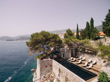 Budva, Karadağ - 12 Temmuz 2020: Karadağ 'ın Sveti Stefan adasında havuz kenarında güneşlenmek için dinlenme yerleri.