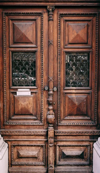 Portas de madeira marrom com janelas e esculturas barradas. — Fotografia de Stock