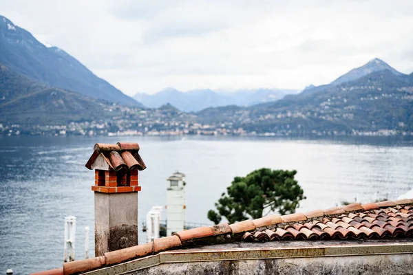 Una antigua chimenea en la azotea con vistas al agua, las montañas y el asentamiento. —  Fotos de Stock