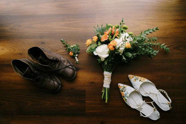 El ramo de novias con grandes rosas blancas y los novios boutonniere con zapatos blancos para mujer y zapatos marrones para hombre con cordones desatados. —  Fotos de Stock