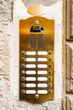 Dahili telefon altın gibi, düğmeleri ve taş duvardaki daire numaraları için boş sütunları olan metal..