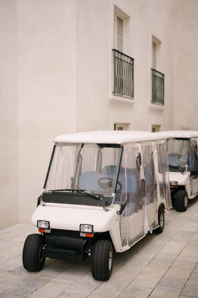 Carrinho de golfe com um toldo transparente estacionado no estacionamento perto do hotel. — Fotografia de Stock