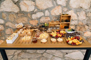 Tahta masa, arkaplanda peynir, meyve ve prosciutto ile servis edilir..