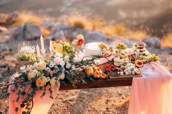 Meja yang dihias untuk perayaan pernikahan dengan karangan bunga mawar putih, buah-buahan dan kue. — Stok Foto