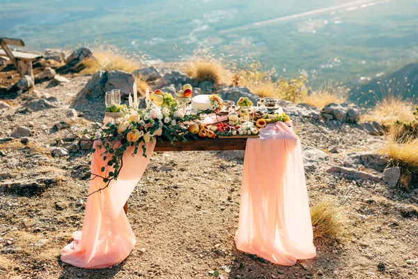 Bruidstafel versierd met bloemen en stof in de vorm van een trein en geserveerd met lekkernijen in een pittoreske plek in de natuur. — Stockfoto