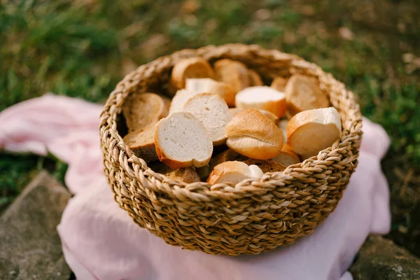 Um close-up de uma cesta de vime cheia de fatias de pão fresco em um tapete de pano rosa. — Fotografia de Stock