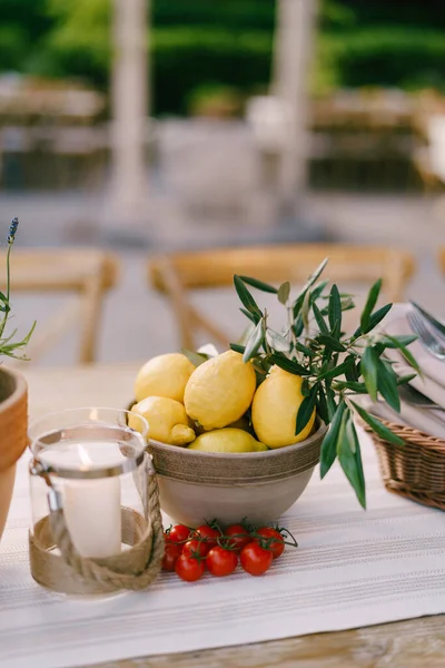 Placa profunda con limones sobre la mesa con una ramita de tomates cherry sobre un fondo borroso. — Foto de Stock