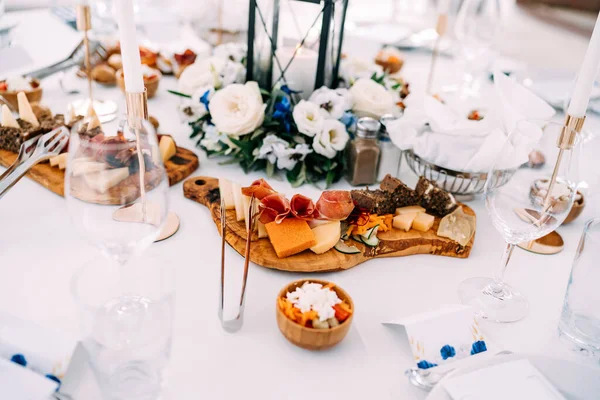 Una mesa festivamente decorada con tablas de cortar y delicadezas en ellos. — Foto de Stock