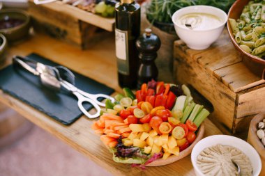 Bir tabak domates, salatalık ve dolmalık biber bir şişe zeytinyağının yanındaki ahşap masada..