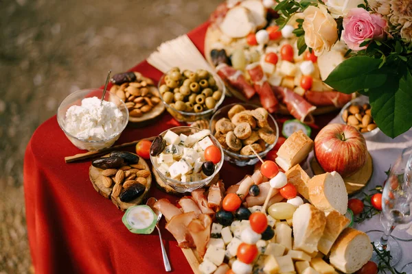 Крупный план стола с салатами с сыром Dor Blue, оливками и миндалем на красной скатерти. — стоковое фото