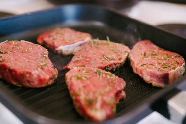 Dört çiğ biftek ızgarada kızartılmış..