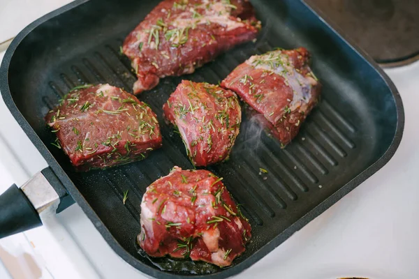 Vier rohe Steaks werden in der Grillpfanne gebraten. — Stockfoto