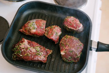 Dört çiğ biftek ızgarada kızartılmış..