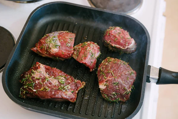 Dört çiğ biftek ızgarada kızartılmış..