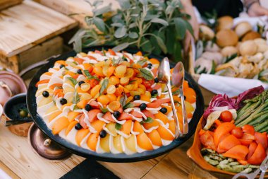 Caprese sebze aperatiflerinin yakın plan çekimi. Sebze dilimleri ve saksıda çiçekler olan bir tabakta..
