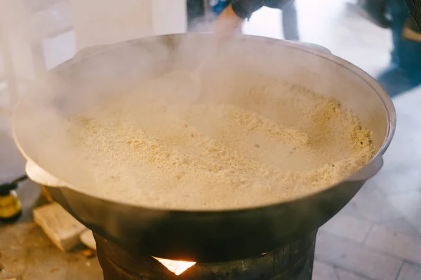 Nasi mentah dituangkan ke dalam kuali besar dengan pilaf. — Stok Foto