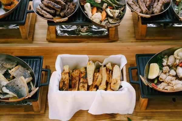 Włoski chleb focaccia, smażone kawałki ryb, kiełbasy i warzywa duszone w miedzianych patelniach w kuchni. — Zdjęcie stockowe