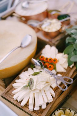 Erimiş peynir ve arkaplanda kavun olan ahşap bir tahtanın üzerinde bir tutam kiraz domatesi..