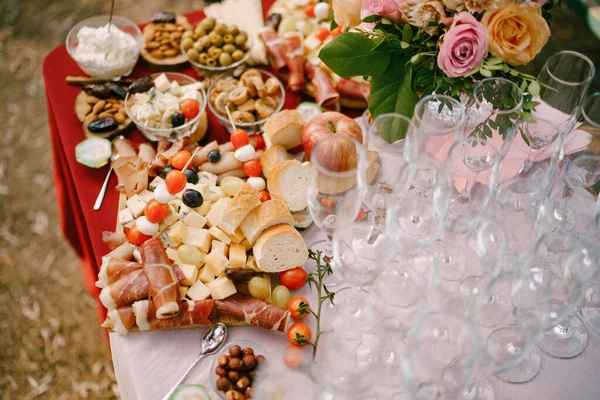 Очки для шампанского на столе с деликатесами и букет роз. — стоковое фото
