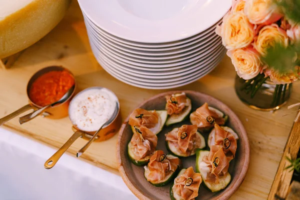 Primer plano de un plato con higos y jamón sobre una mesa de madera con platos limpios vacíos y un ramo de rosas. — Foto de Stock