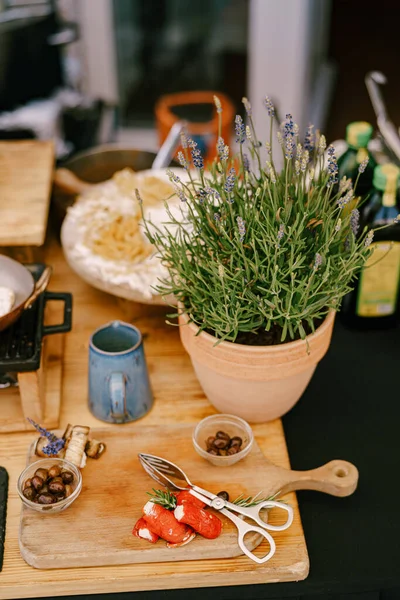 Lavanda em um vaso de flores na mesa da cozinha com uma caneca azul e uma tábua de corte de madeira. — Fotografia de Stock