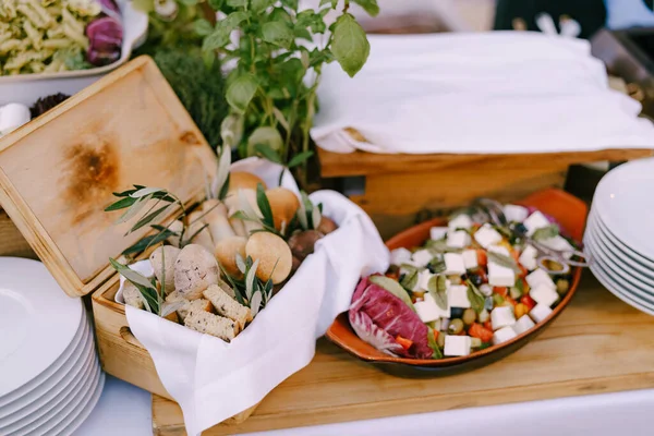 Caja de madera con palitos de pan y croutons en la mesa con platos limpios y ensalada. — Foto de Stock