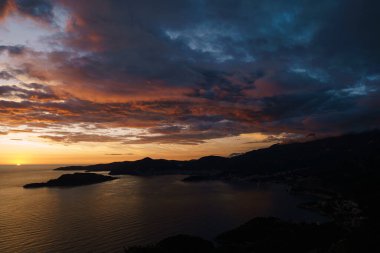 Karadağ 'daki Budva Riviera ve St. Nicholas adası üzerinde gün batımında alevli kırmızı ve mavi gökyüzü.