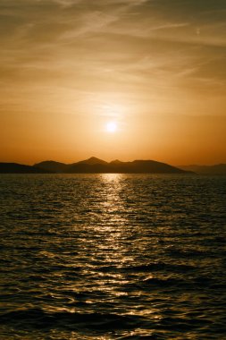 Ufuktaki dağlar ve denizin üzerinde hoş bir gün batımı..