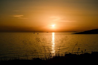 Gün batımında, ufukta yelkenli var. Hırvatistan açıklarında, Adriyatik Denizi 'nde güneşli bir patika ile kızgın sarı bir günbatımı.