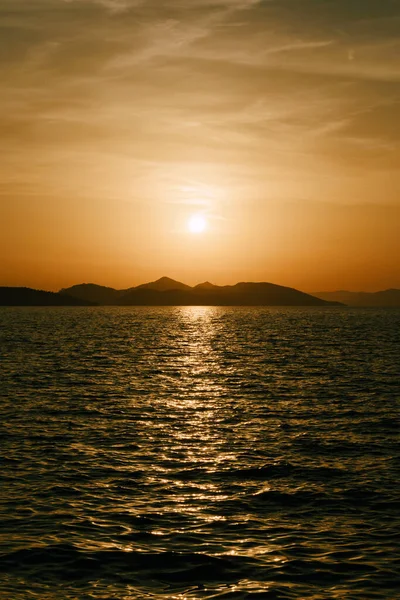 A delightful sunset over the sea and mountains on the horizon. — Stock Photo, Image