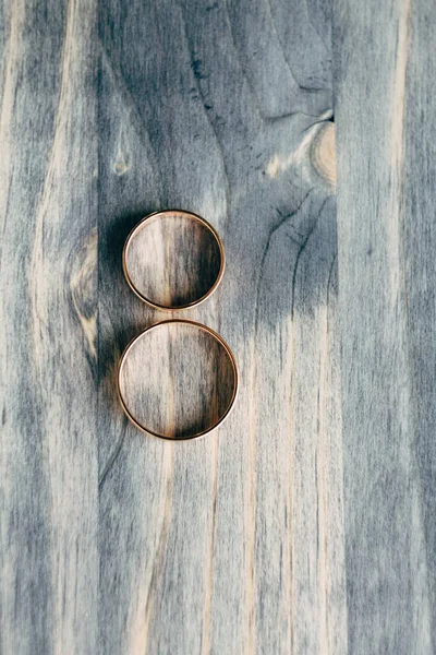 Vista superior de dois anéis de casamento de ouro lado a lado na textura de madeira cinza. — Fotografia de Stock