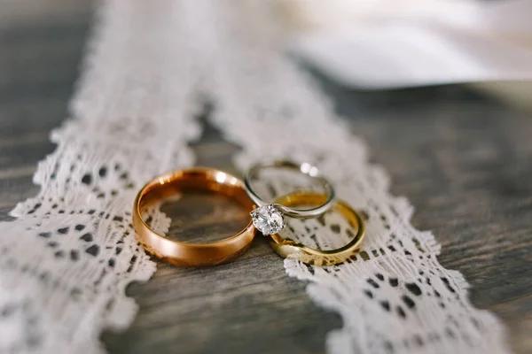 Γκρο πλαν από χρυσές βέρες και λευκά χρυσά δαχτυλίδια για τη νύφη σε λευκή δαντέλα. — Φωτογραφία Αρχείου