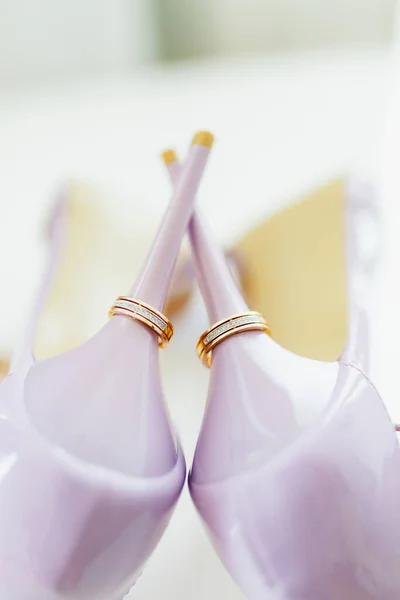 Pernikahan cincin emas di tumit sepatu pengantin ungu. — Stok Foto