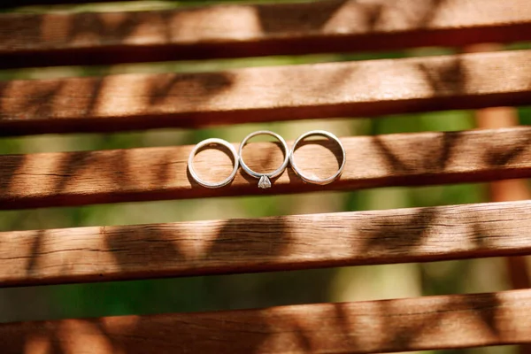 Anéis de casamento de ouro e um anel de noivado em tablets de madeira. — Fotografia de Stock