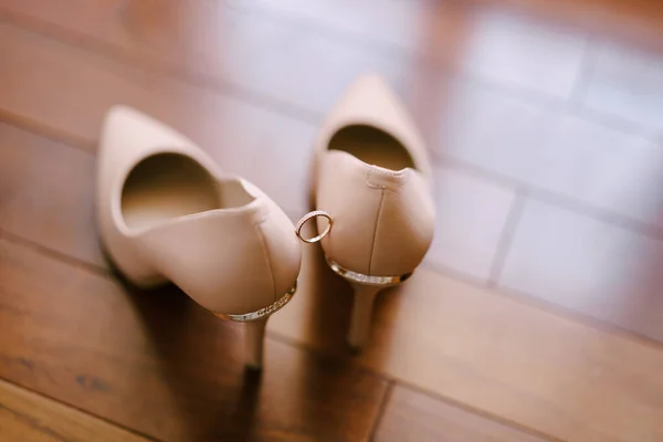 Svatební prsten na nevěsty krémové boty na rozmazaném pozadí. — Stock fotografie