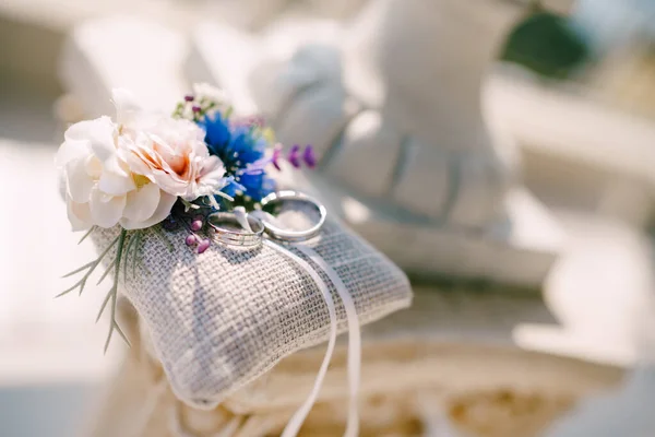 Anillos de boda en oro blanco sobre una almohada con flores. —  Fotos de Stock