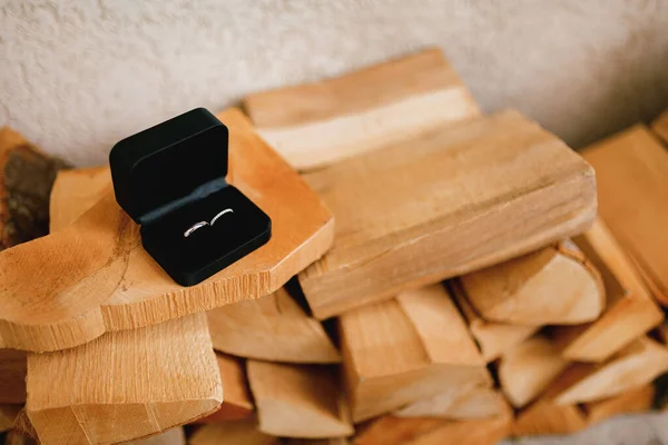Cincin emas pernikahan dalam kotak beludru hitam di kayu cincang. — Stok Foto
