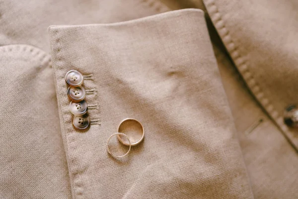 Dos anillos de boda de oro en la manga de una chaqueta beige para hombre con botones. —  Fotos de Stock