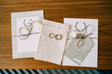 Altın alyanslar kumaş bir çantada. Gelin ve damadın yeminleriyle yaprakların arasında..