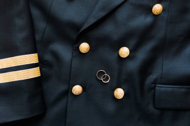 İki başlı kartallı siyah ceketli iki altın alyansın üst görüntüsü..