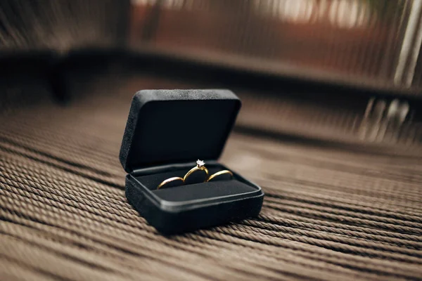 Anillos de boda y un anillo de compromiso con una gran joya en una caja de terciopelo negro. —  Fotos de Stock