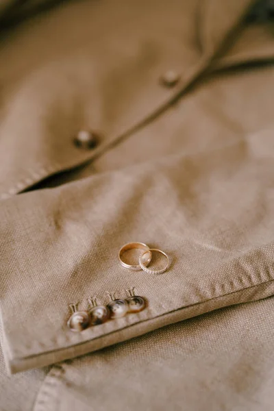 Dos anillos de boda de oro en una chaqueta de hombre beige con botones. —  Fotos de Stock