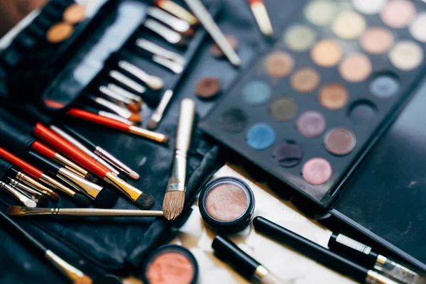 Makyöz seti. Farklı renklerde bir palet ve siyah bir makyaj çantasındaki allık ile makyaj fırçaları..