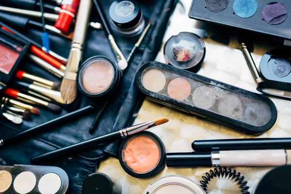 Set profesional para aplicar maquillaje con pinceles, paleta de sombra de ojos y rímel esparcidos sobre la mesa. Maquillaje artista conjunto. — Foto de Stock