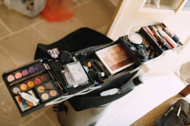 Makyöz seti. Göz farı, allık ve ruj sürmüş parlak bir odada geniş bir kozmetik çanta..