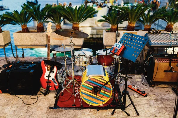 Sebuah platform untuk musisi dengan instrumen musik, drum kit, gitar dan konsol sound engineer terhadap latar belakang meja meriah oleh air. — Stok Foto